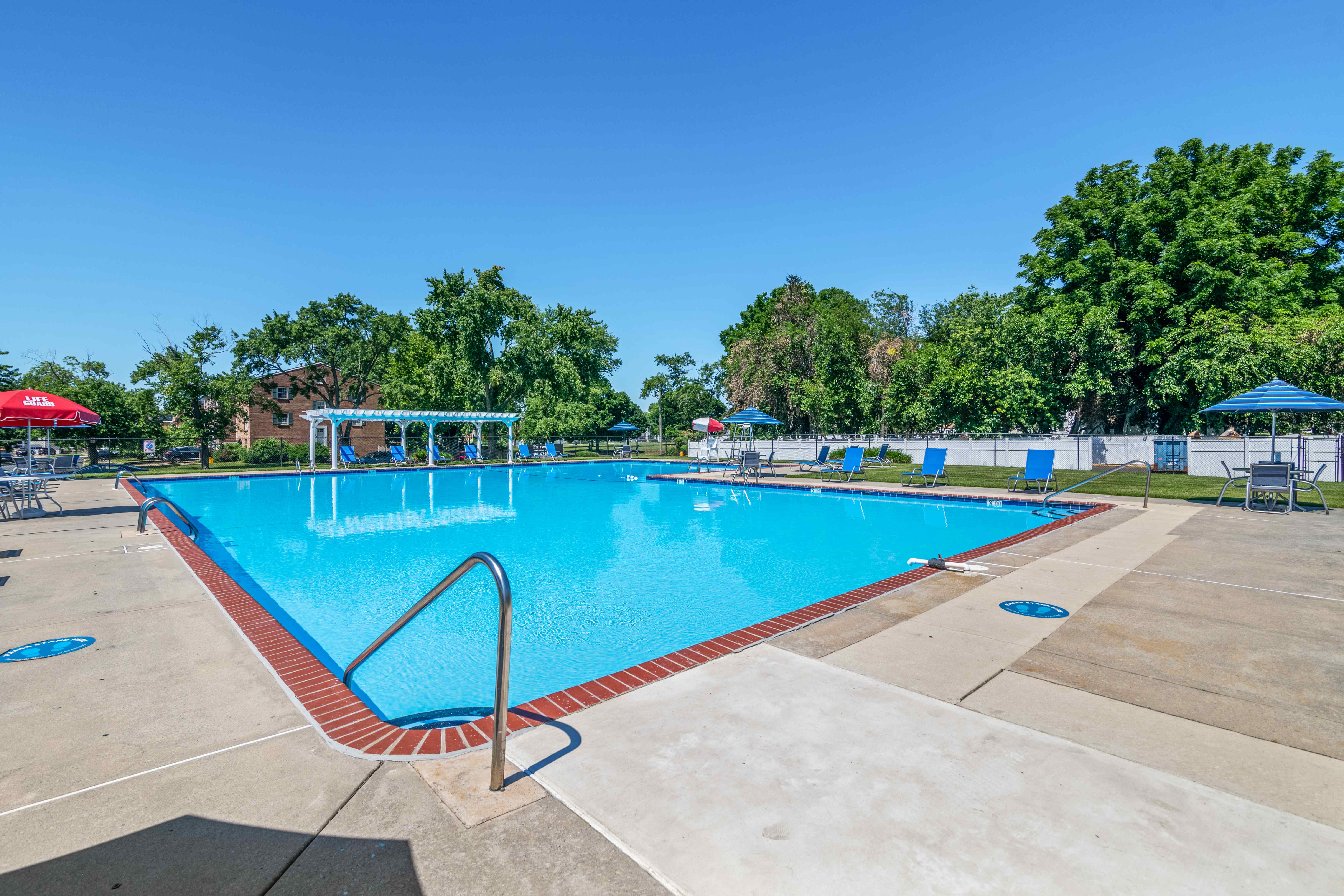 A large blue swimming pool with a red and white ladder.